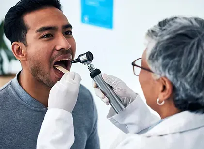 Dentist examining a patient's mouth with a light during an oral cancer screening