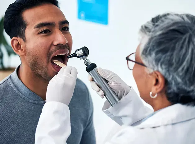 Dentist examining a patient's mouth with a light during an oral cancer screening